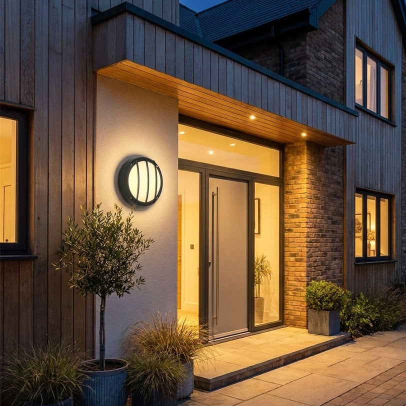 Byrzi outdoor wall light beside a glass panel entrance with potted plants