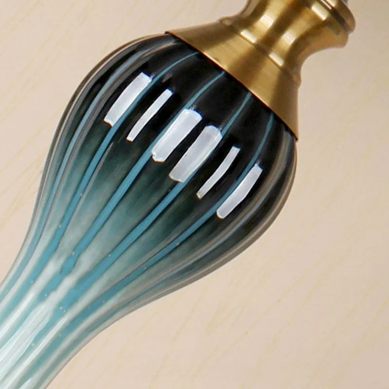 Close-up of the elegant, sculpted teal central accent on the antique brass cerf floor lamp pole