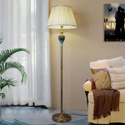 Vintage beige pleated fabric cerf floor lamp with an antique brass finish base in a cosy living room