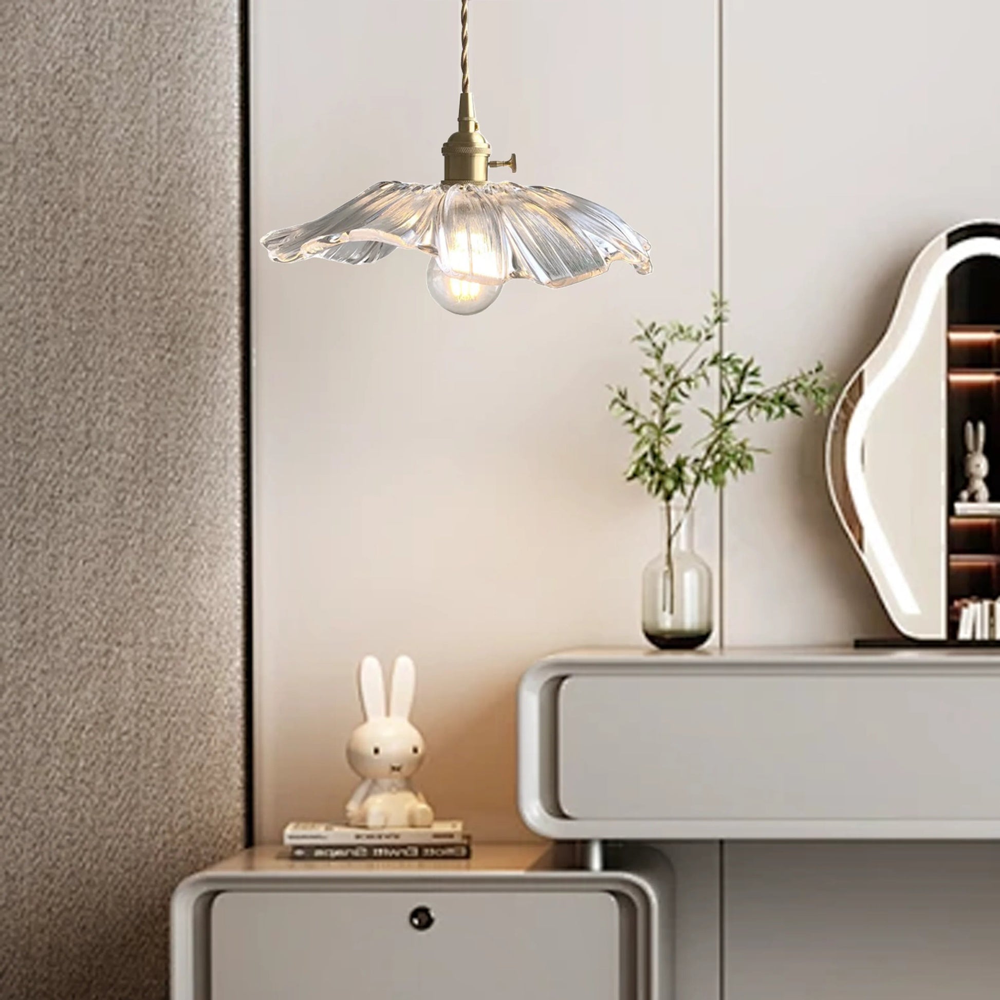 Clear lotus glass pendant used as elegant bedside lighting next to a modern cabinet