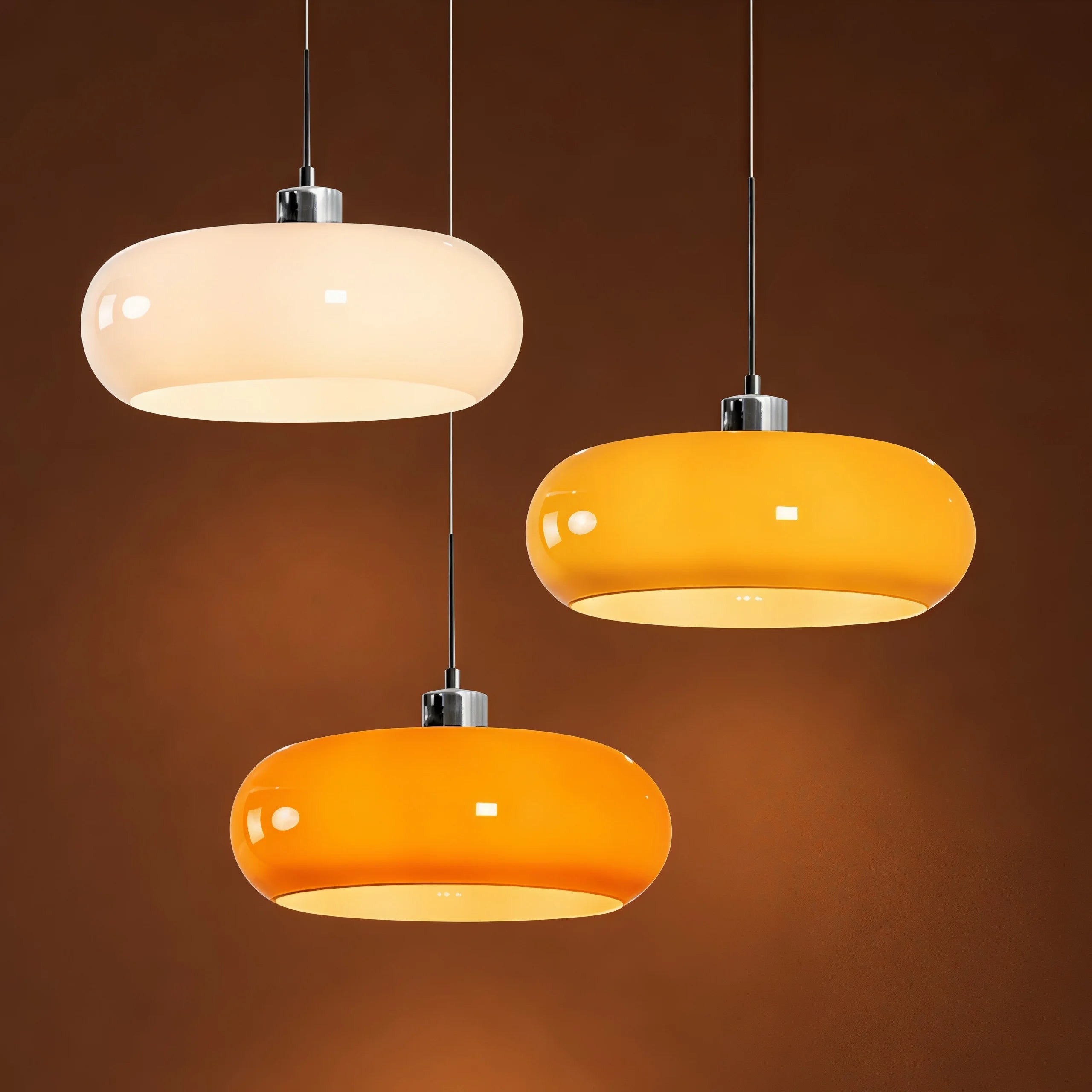 Cluster of three retro glass dome pendant lights in white, brown, and orange illuminating a dark setting