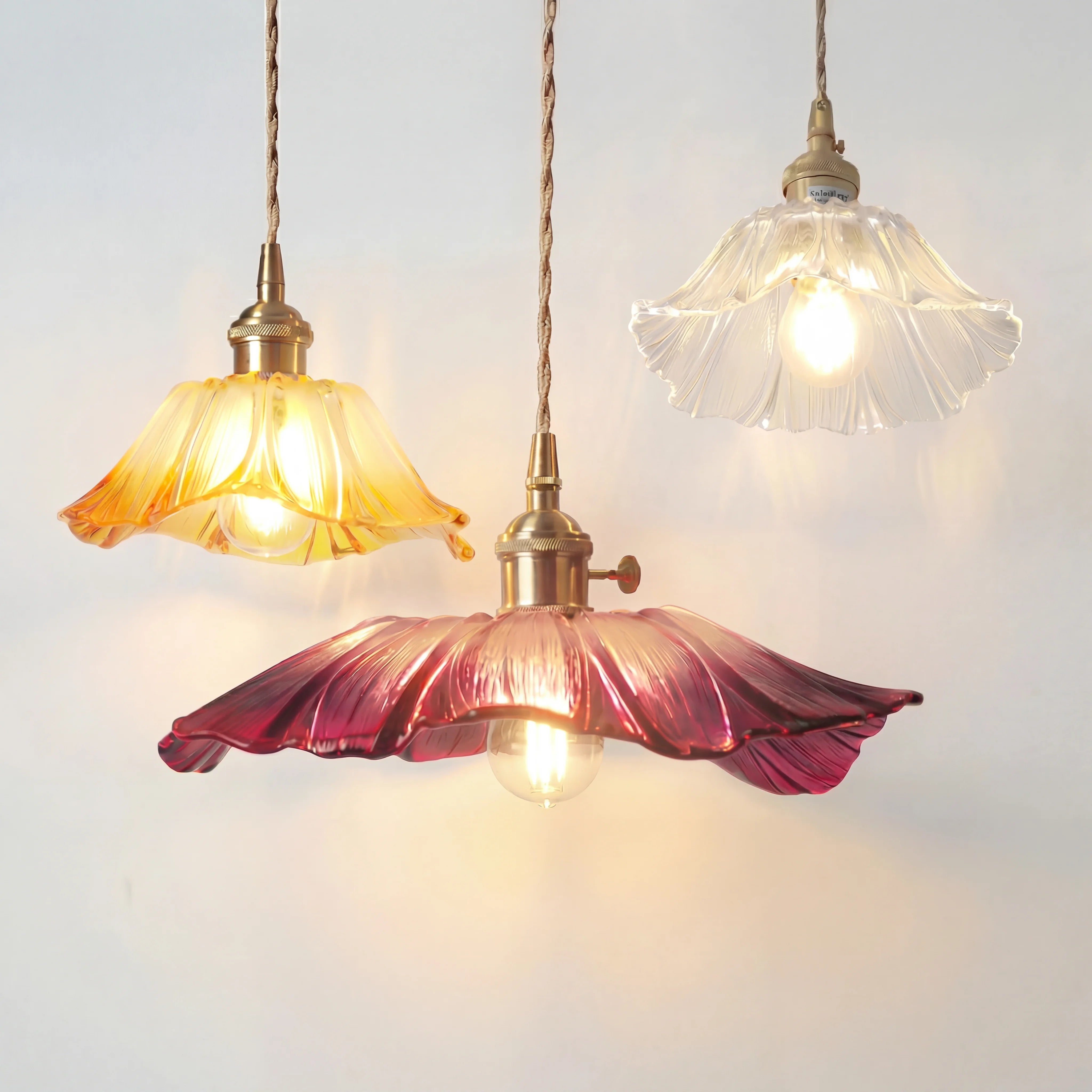 Cluster of three retro floral glass pendants in yellow, purple, and clear illuminating together