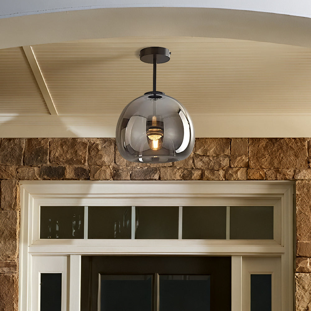 Compact smoke grey glass globe ceiling light installed on a covered rustic brick porch