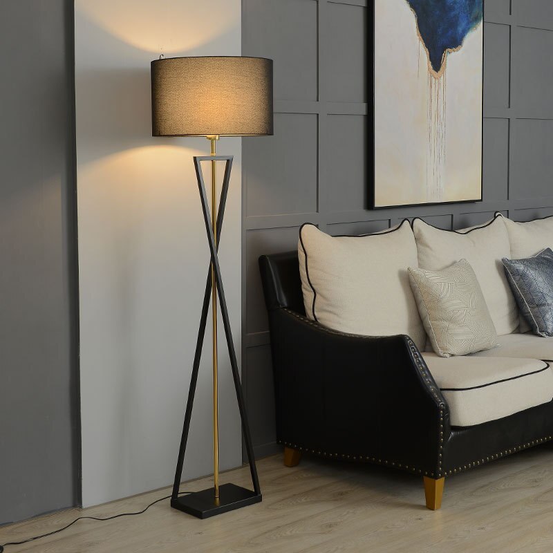 Contemporary tripod standing light with an intersecting metal base placed beside a modern living room sofa