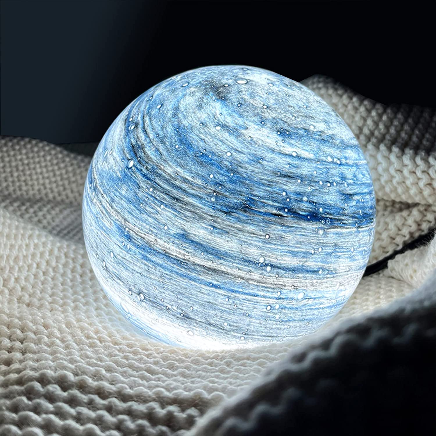 Cosy blue glass orb lamp providing a soothing wash of light on a textured white knitted blanket
