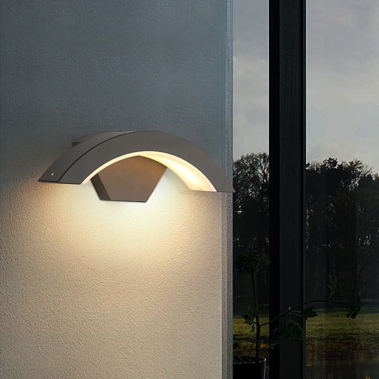 Curved black LED outdoor lighting fixture mounted on a modern architectural pillar