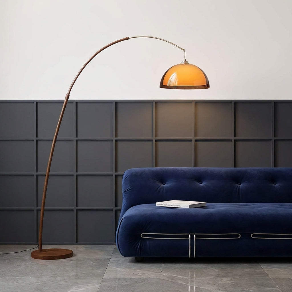 Close up of the Dalzi arc floor lamp's amber dome shade over a navy sofa against a dark panelled wall