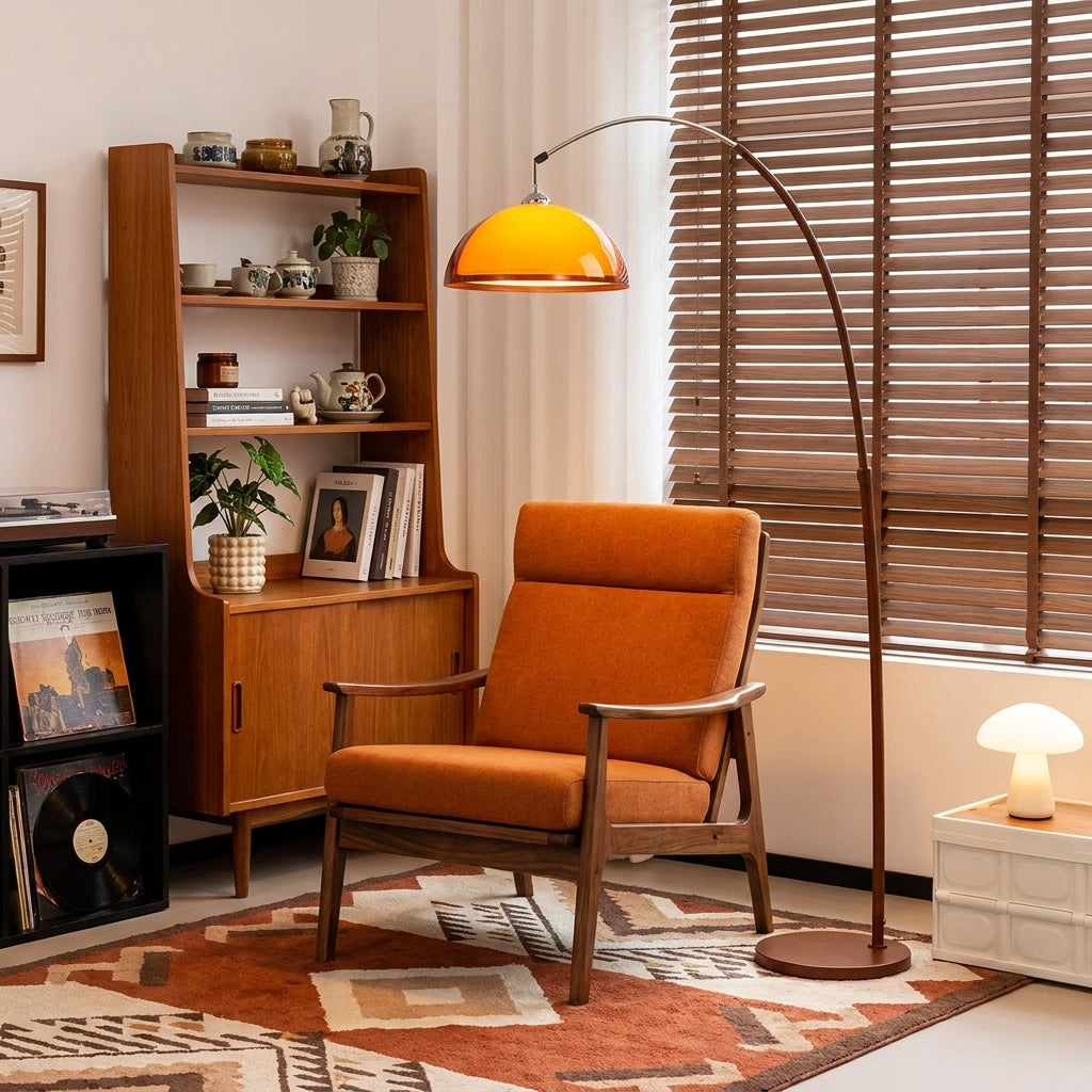Dalzi arc floor lamp in a cosy reading corner beside an orange chair and wooden bookshelf