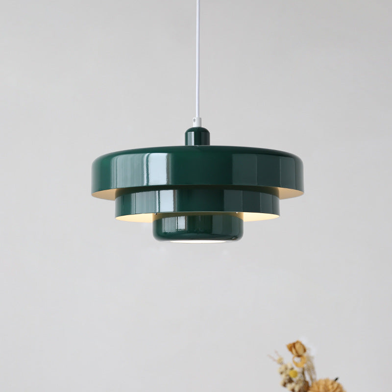 Sleek dark green mid-century Bauhaus tiered pendant lamp isolated on a light neutral background