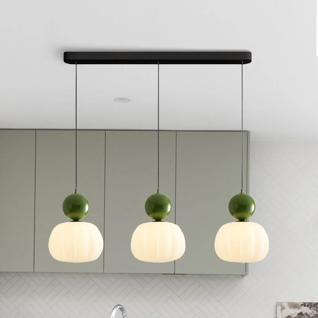 Green three-head debz linear pendant light illuminating a sleek modern kitchen island