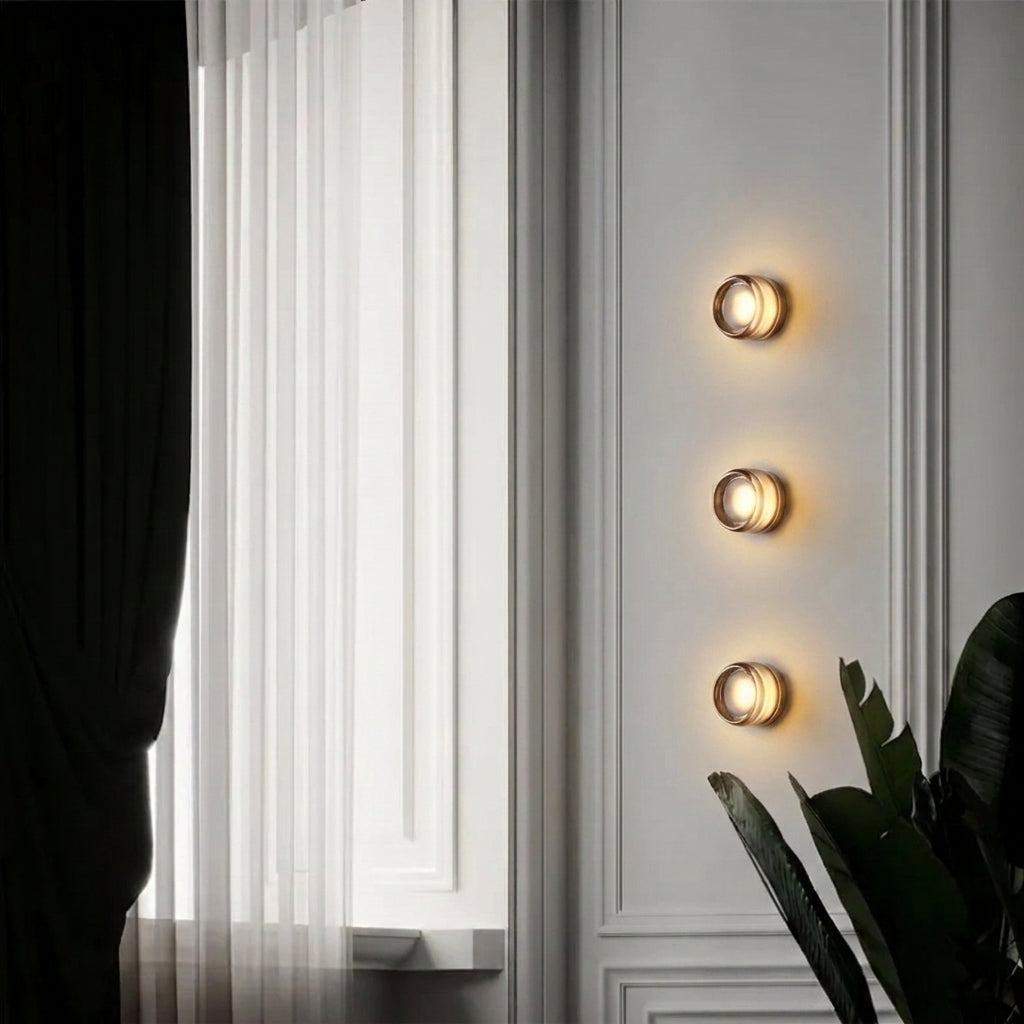 Three Doxlu grey glass wall sconces in a vertical row beside a curtained window