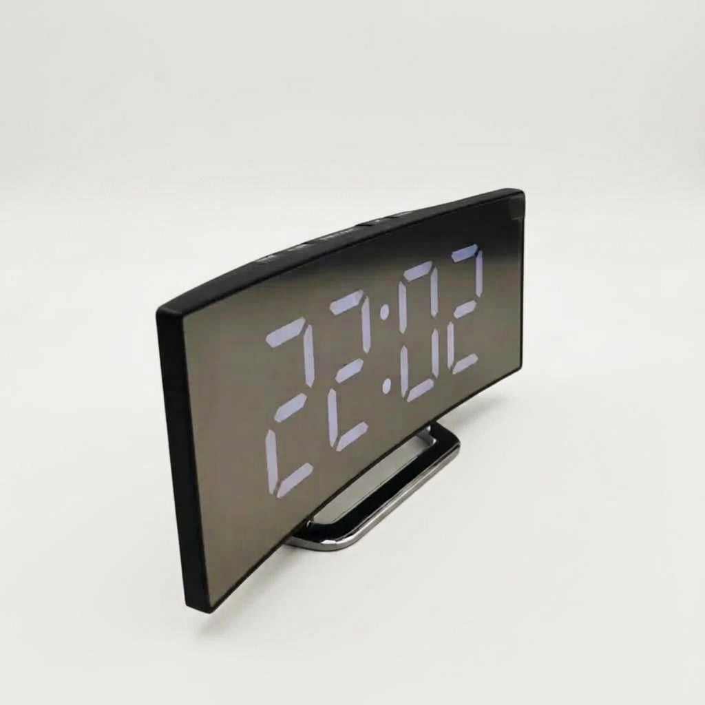 A modern digital alarm clock with a black frame showing the time 22:02 in white LED digits, resting on a small metallic stand against a plain light grey background.