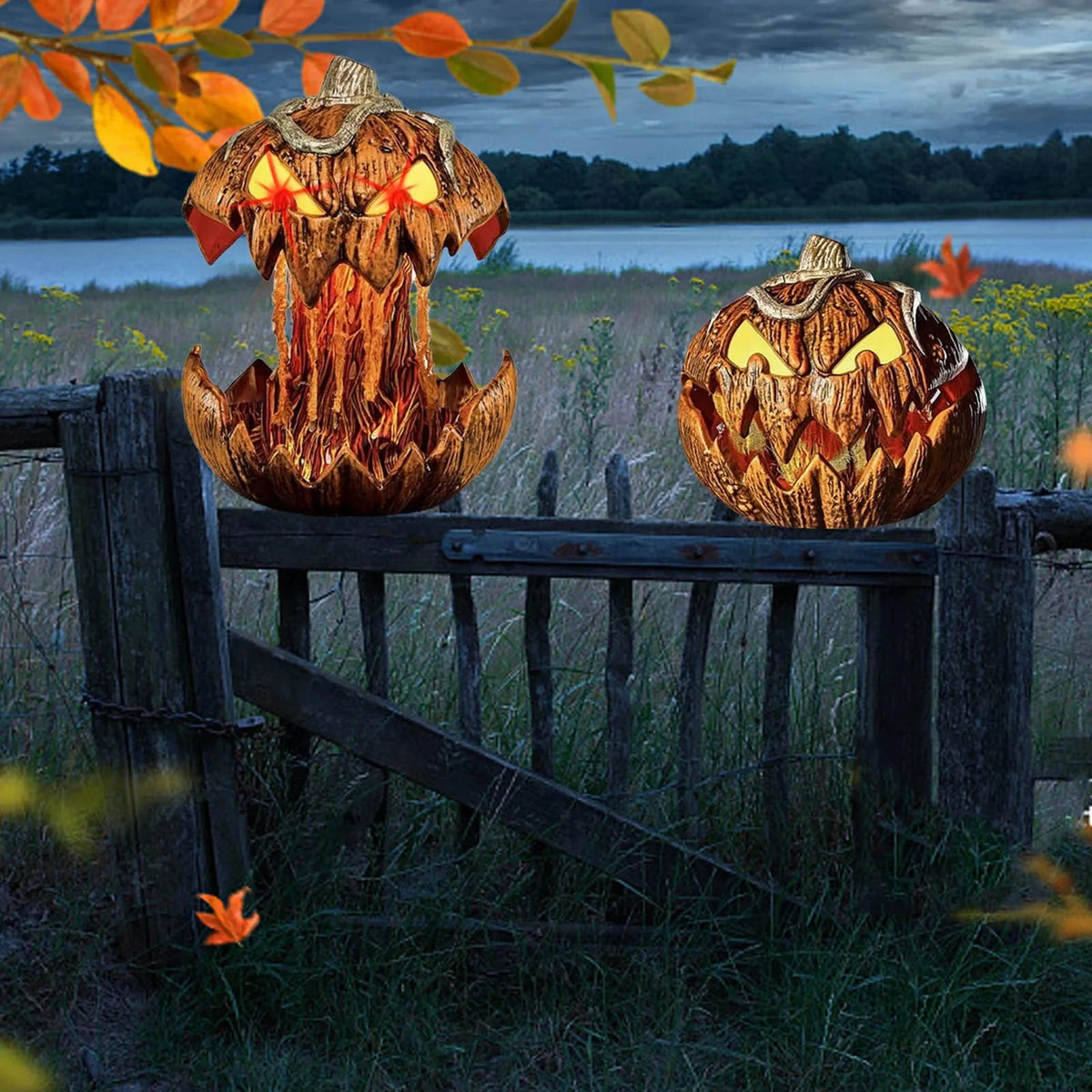 Two jack-o'-lantern pumpkins with glowing yellow lights sit on a rustic wooden fence in an outdoor field near water, with autumn leaves in the foreground and a dark cloudy sky behind.