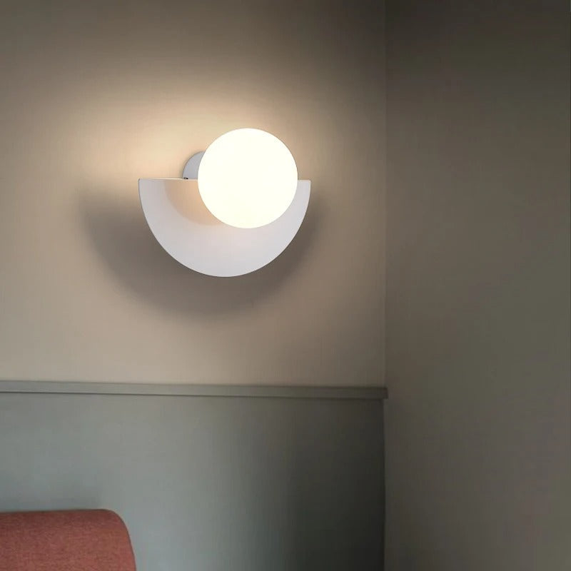 Modern fers white geometric semi-circle wall sconce with a frosted glass globe illuminating a minimalist room