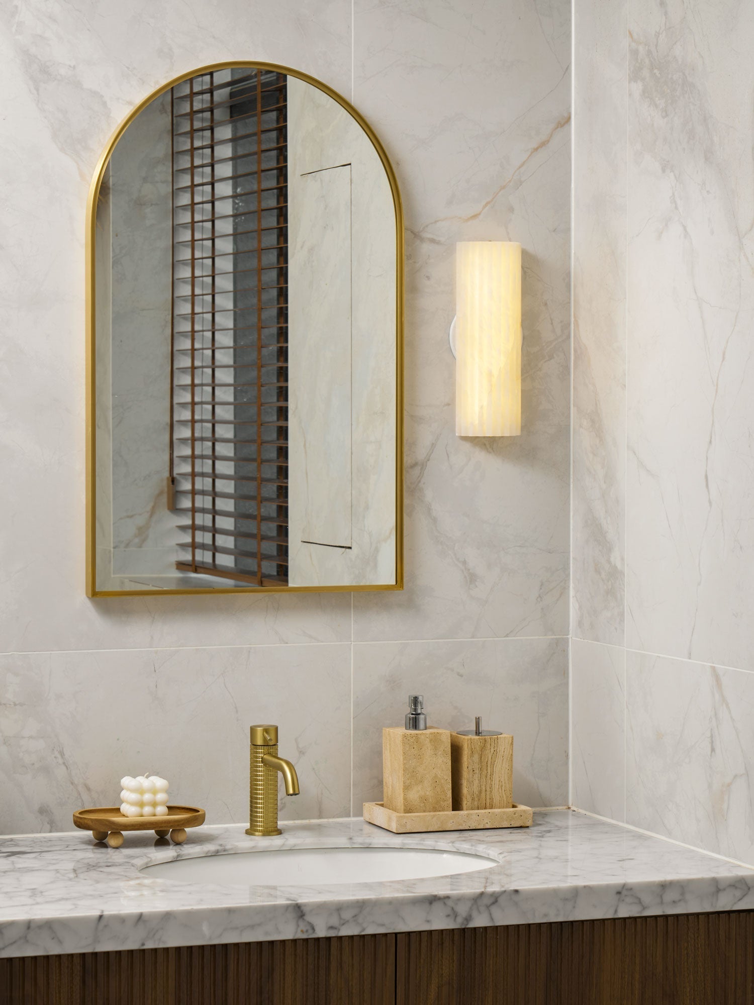 Fluted marble wall lamp providing sophisticated ambient light in a bright, modern washroom