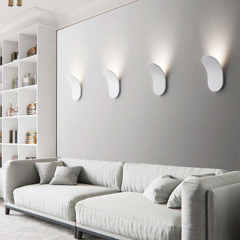 Series of four white Nordic wall lamps installed in a row above a modern living room sofa