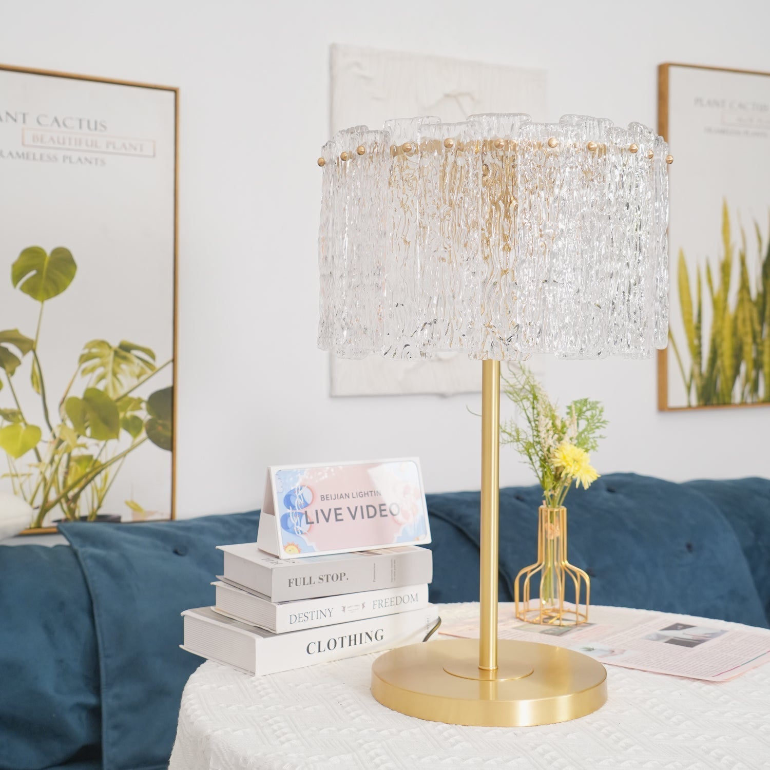 Modern textured glass fyns table lamp styled on a white side table next to a blue living room sofa