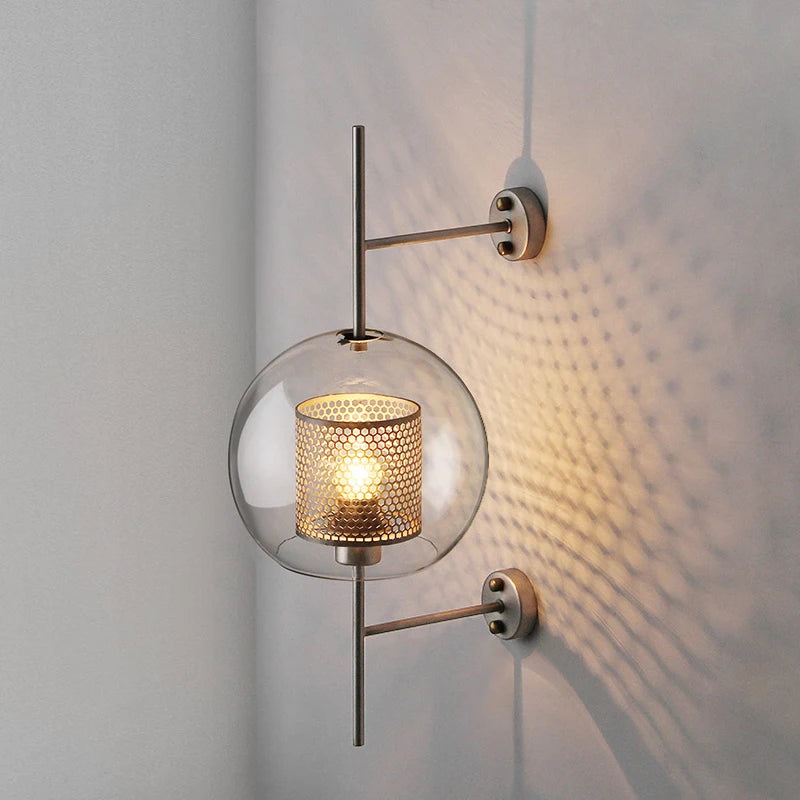 Gexli ball glass wall sconce in bronze finish, lit, casting a dappled honeycomb light pattern on the wall