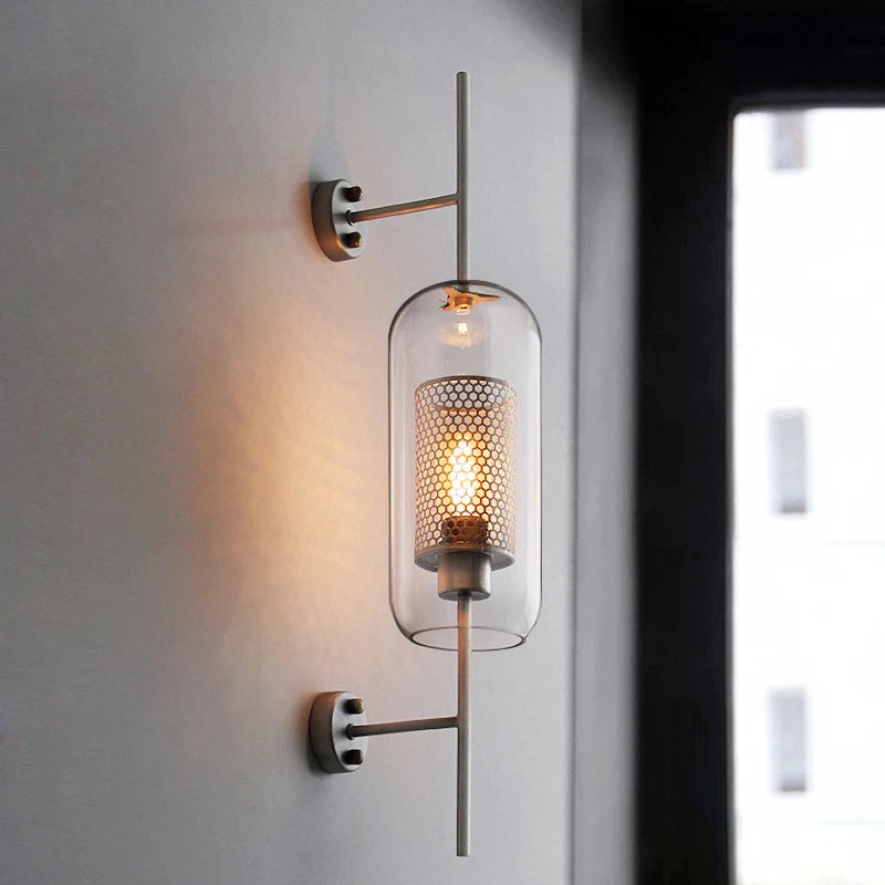 Gexli cylindrical glass wall sconce in bronze finish, mounted beside a window, lit