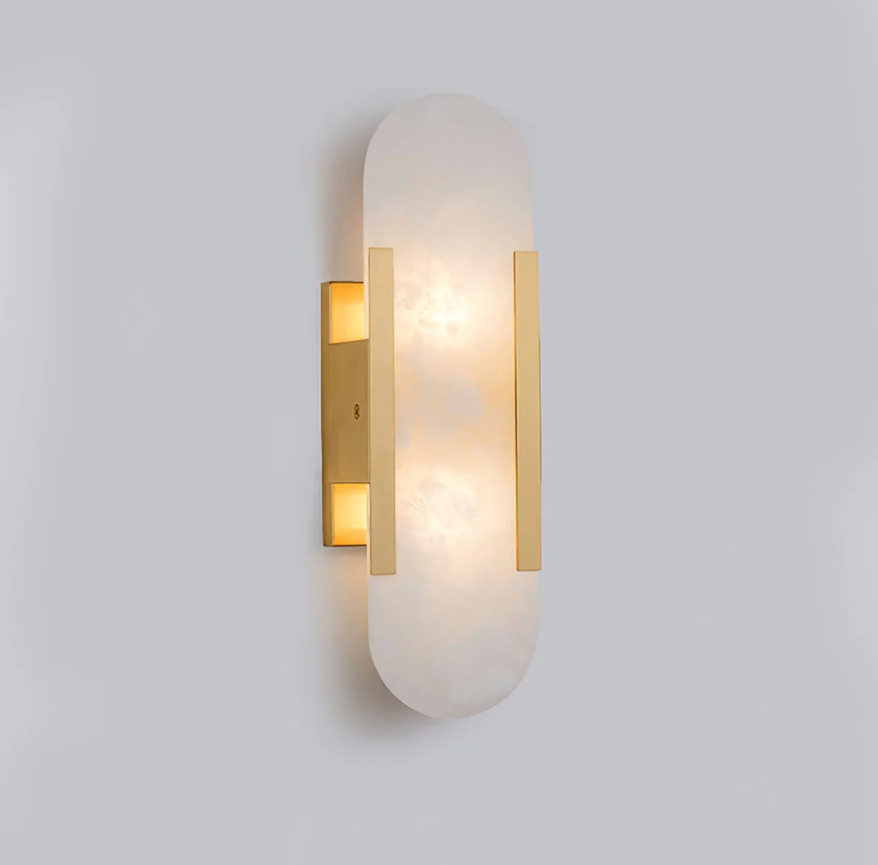 Modern gold dolomite marble pill-shaped wall sconce casting a warm, ambient glow