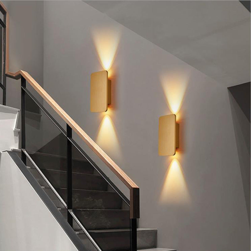 Pair of gold flat panel LED sconces illuminating a contemporary indoor staircase