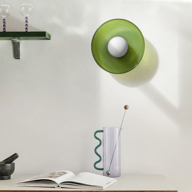 Green glass wall sconce mounted above a minimalist desk and decor