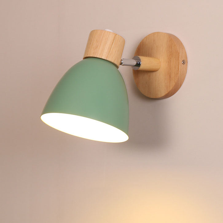 Green Nordic metal and wood wall sconce without a pull cord casting a warm downward glow
