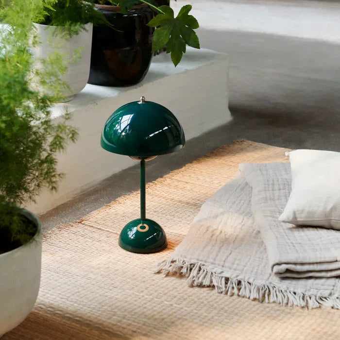 Green portable LED mushroom lamp resting on a textured rug near indoor plants