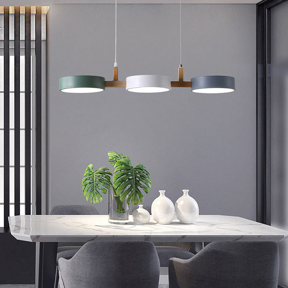 Green, white, and grey linear pendant casting a warm glow over a minimalist dining table