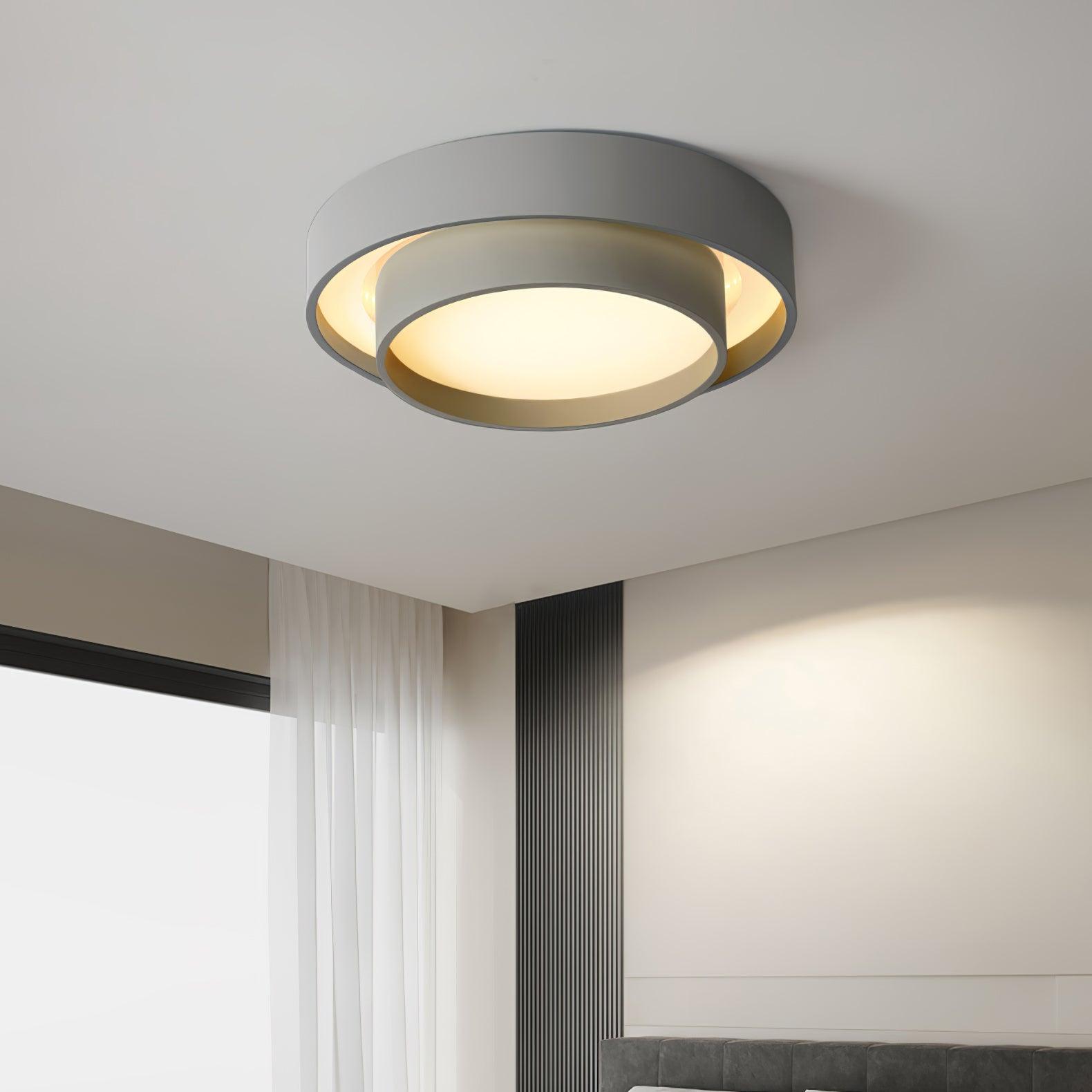 Grey minimalist layered LED ceiling lamp providing soft illumination in a bedroom with a dark accent wall