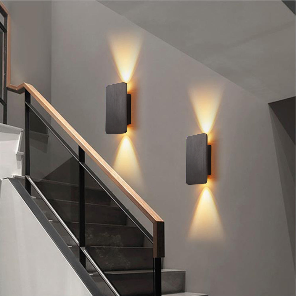 Two grey rectangular LED wall sconces providing elegant architectural lighting up a modern glass staircase