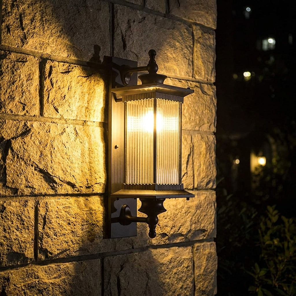 Gumzi exterior lantern wall light glowing at night on a stone wall