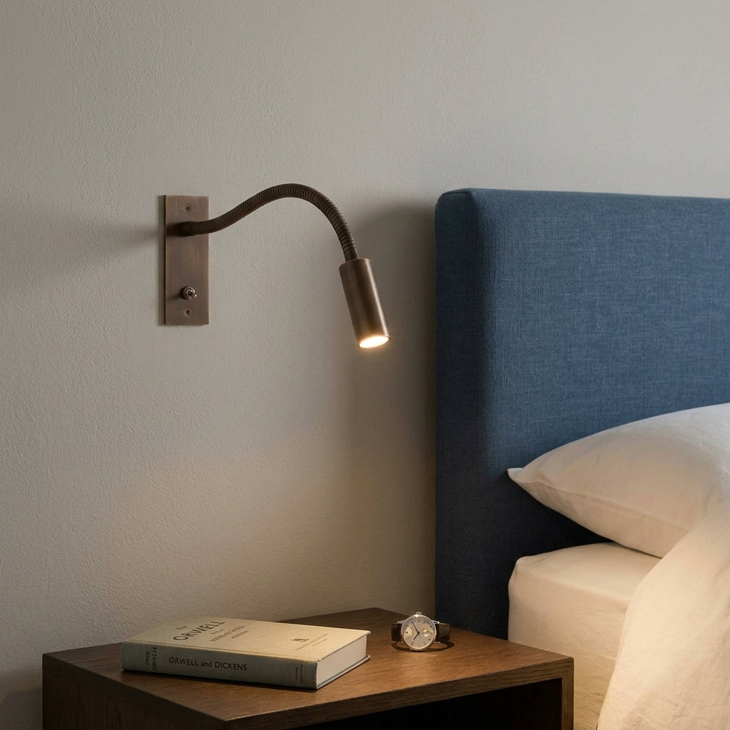 Hulzi bronze gooseneck wall light mounted next to navy upholstered headboard