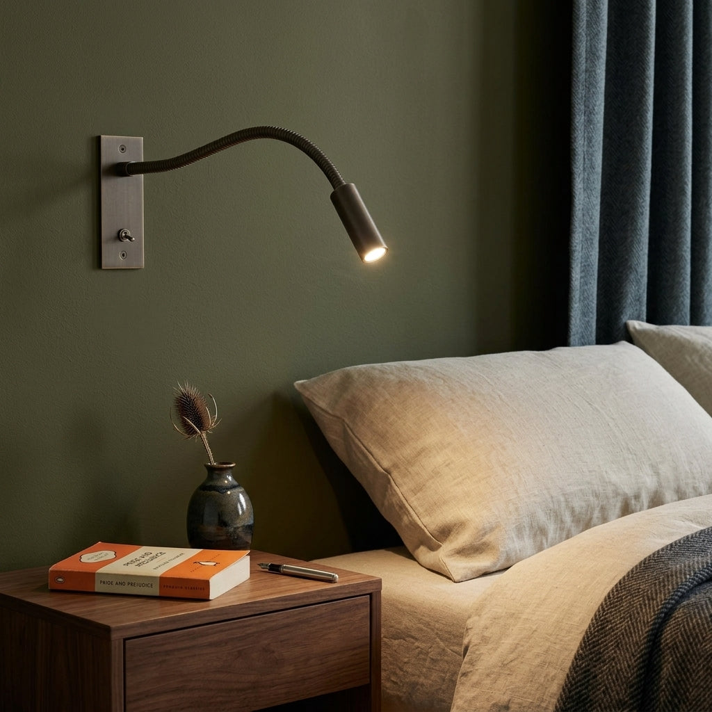 Hulzi bronze gooseneck wall light mounted above an olive green headboard with a book on the nightstand