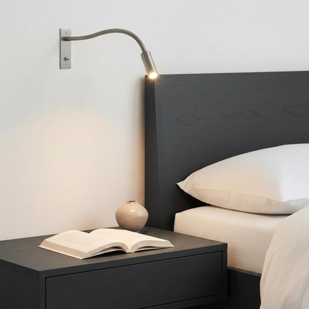 Hulzi nickel gooseneck wall light lit warm above a bed with white linens and an open book