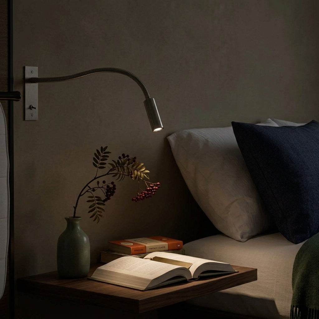 Hulzi nickel gooseneck wall light mounted above a bed with a potted plant and book on the nightstand