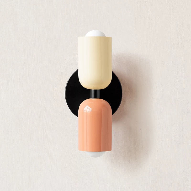 Beige and pink hutre two-tone glass wall light illuminating warmly against a plain wall