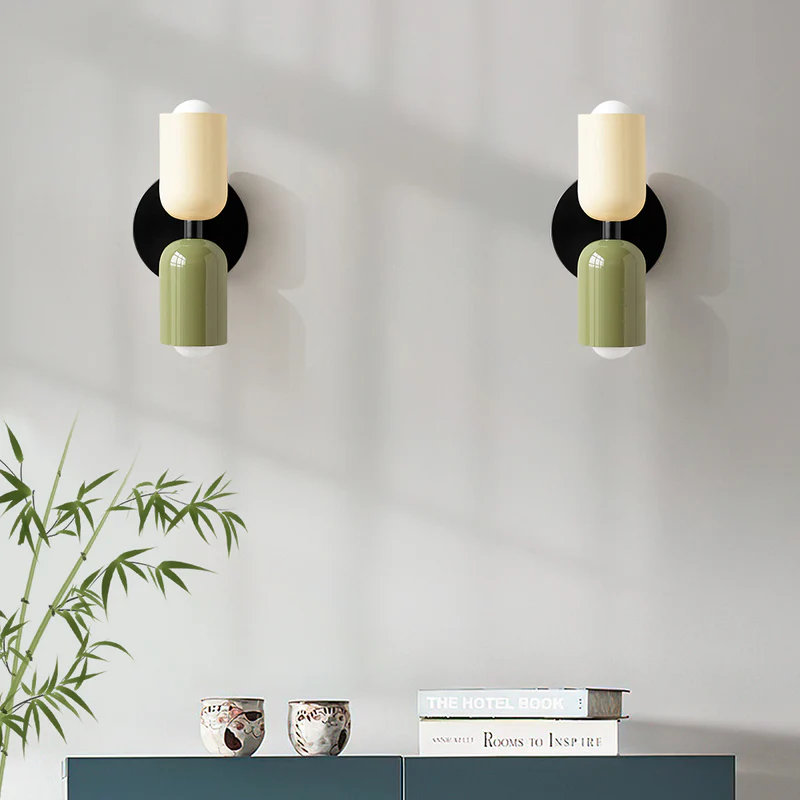 Pair of beige and green hutre capsule wall sconces mounted above a modern blue cabinet