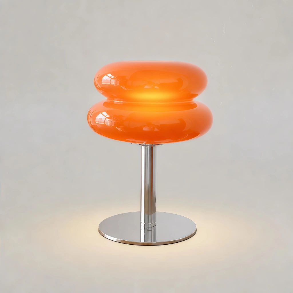 Illuminated orange retro stacked hutyl glass table lamp casting a warm ambient glow in a dim room
