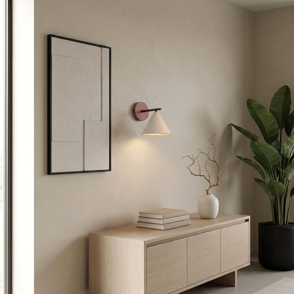 Imzo travertine cone wall sconce mounted above a console table with a framed picture and books