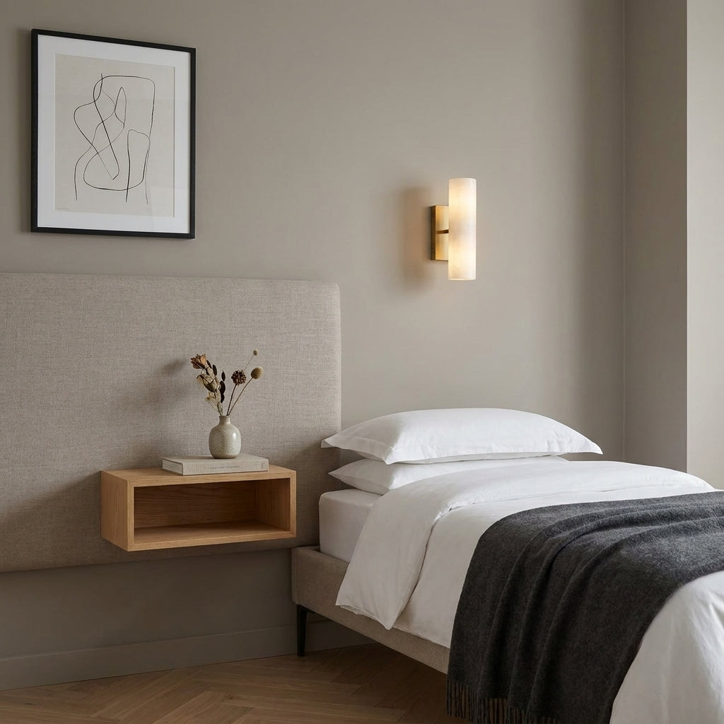 Ivzo brass alabaster wall sconce mounted above a bedroom headboard