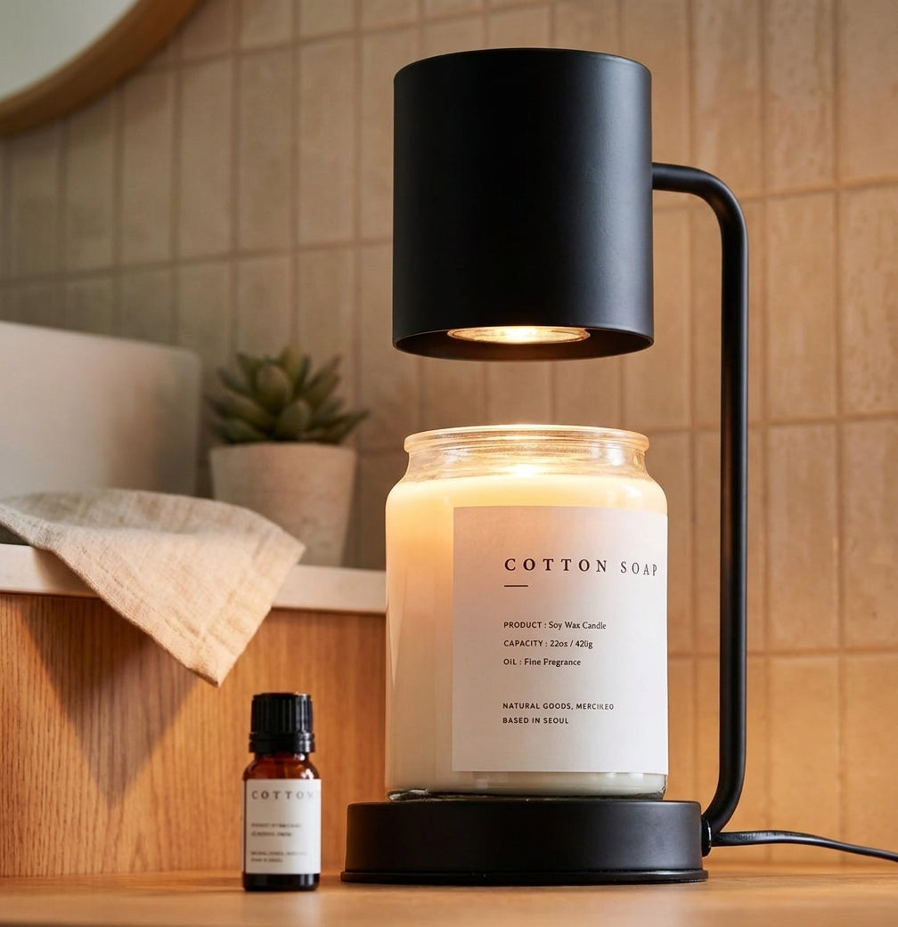Jomzi black candle warmer lamp on a shelf beside towels and fragrance oil