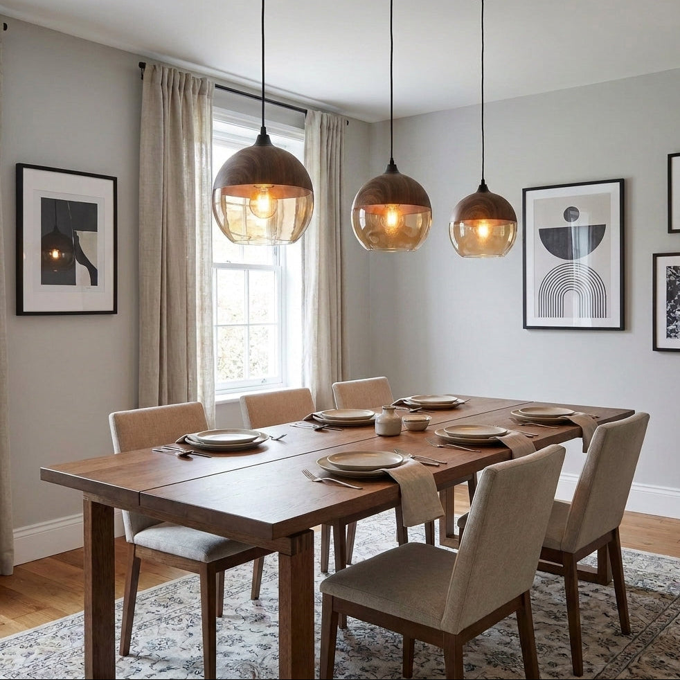 Three Jovli pendant lights hanging over a dining table with framed art on the wall