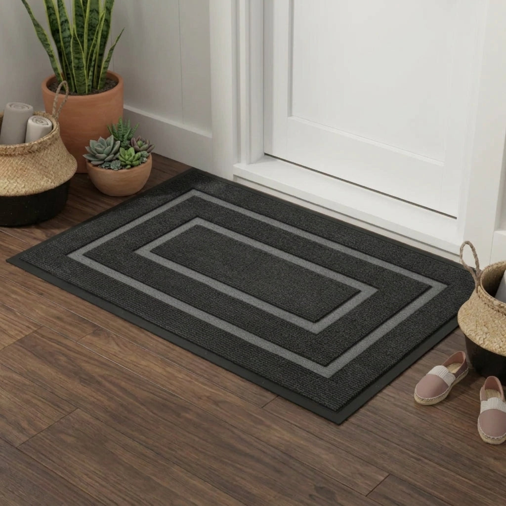 Kalzu black outdoor doormat in front of a white door on wood flooring