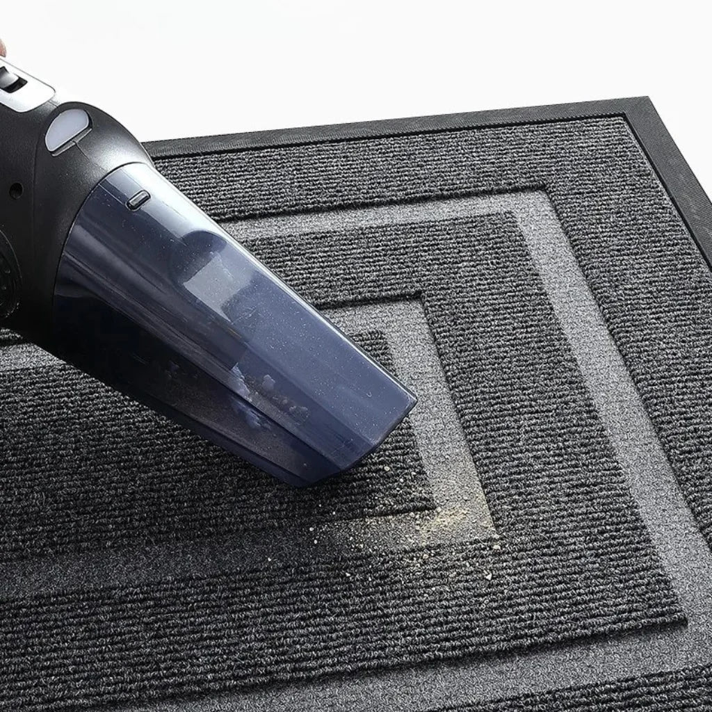 Vacuuming the Kalzu black outdoor doormat with a handheld vacuum cleaner