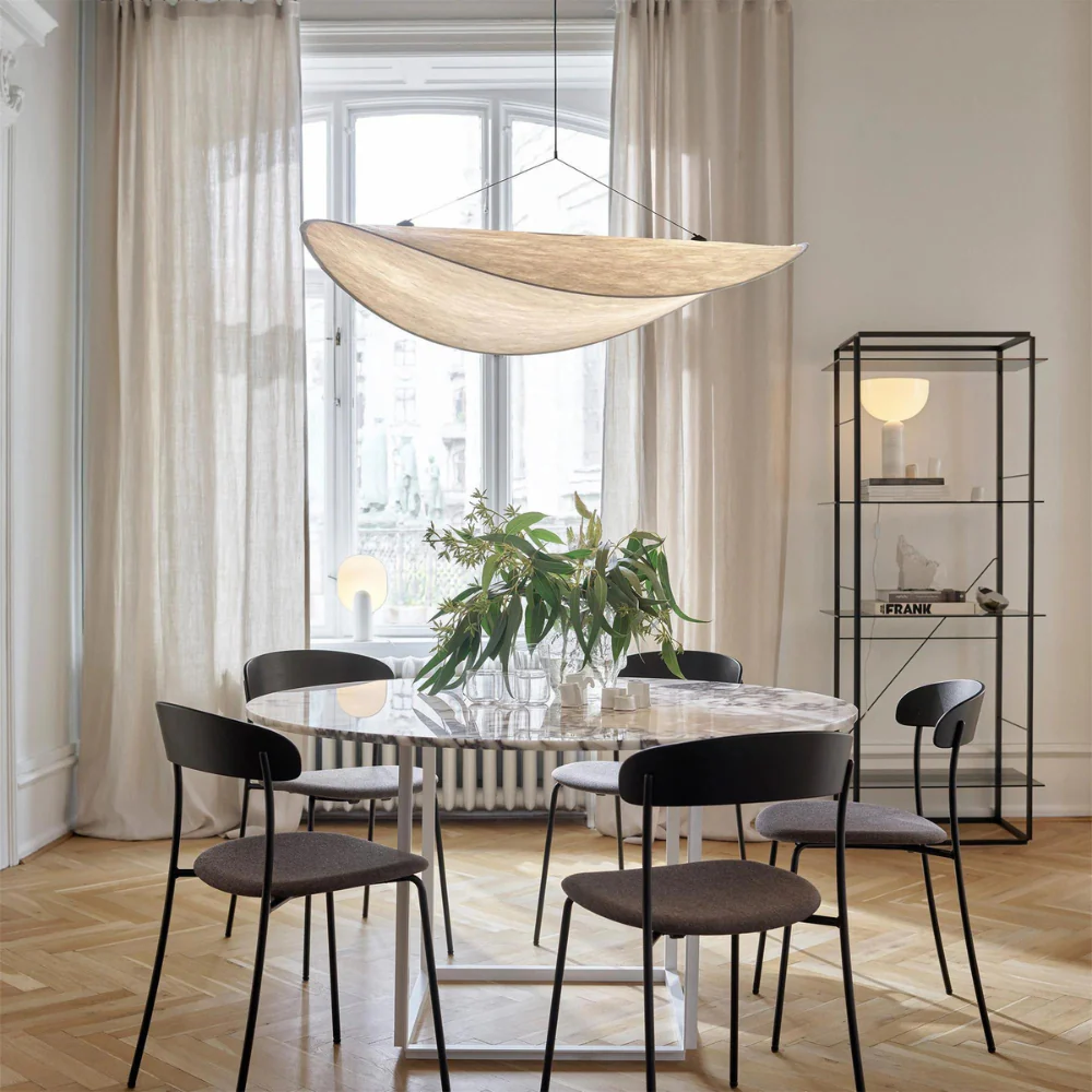 Single Japandi silk wave korta chandelier suspended over a modern round dining table in a sunlit room