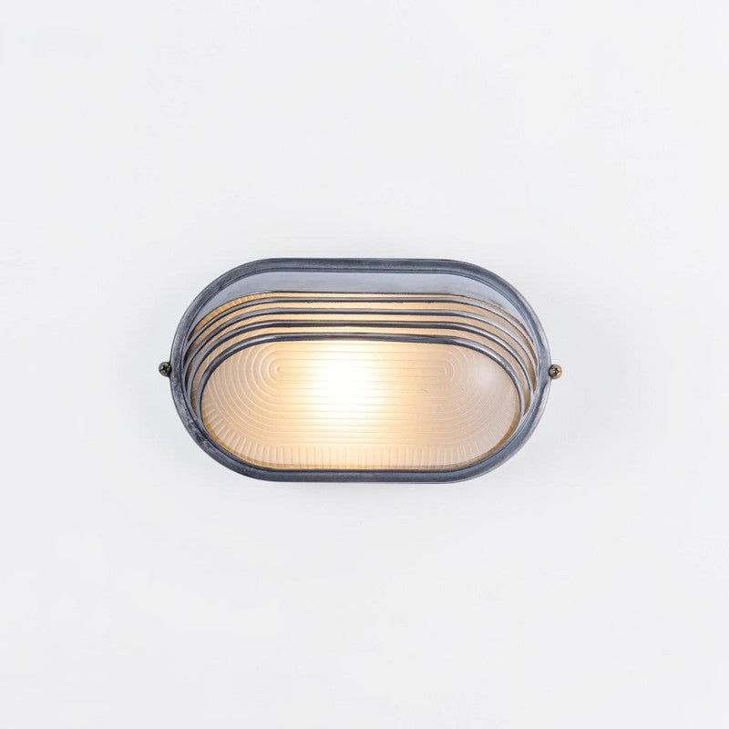 Kuxqa bulkhead wall light in Louvred Cage style, illuminated, angled view on a grey studio background
