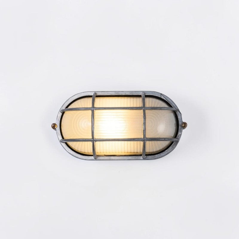 Kuxqa bulkhead wall light in grid cage style, illuminated, on a grey studio background
