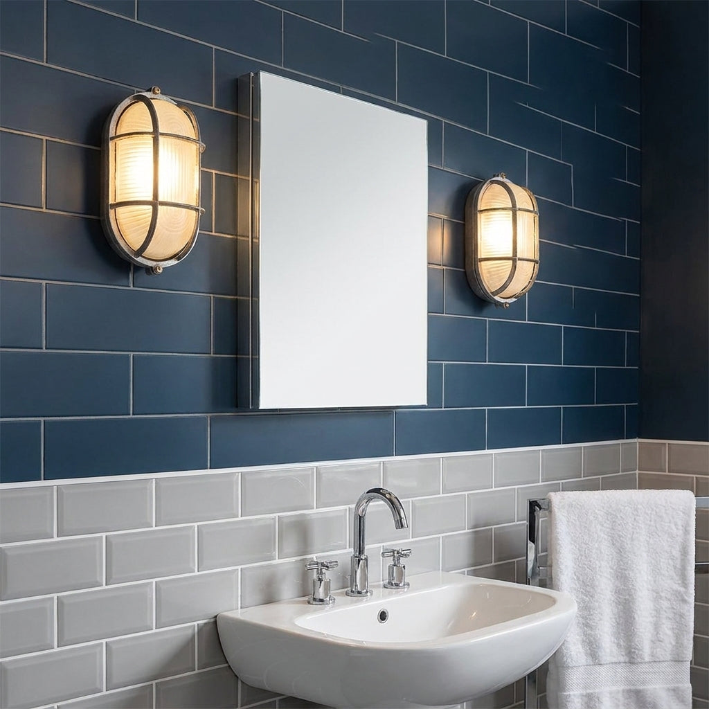 Two Kuxqa bulkhead wall lights mounted either side of a mirror in a dark-tiled bathroom