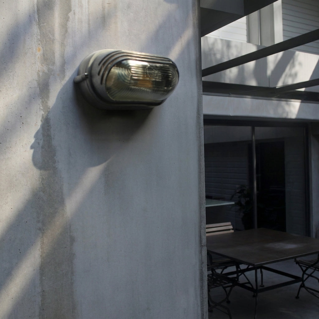 Kuxqa bulkhead wall light illuminated on a light outdoor wall with dramatic shadow